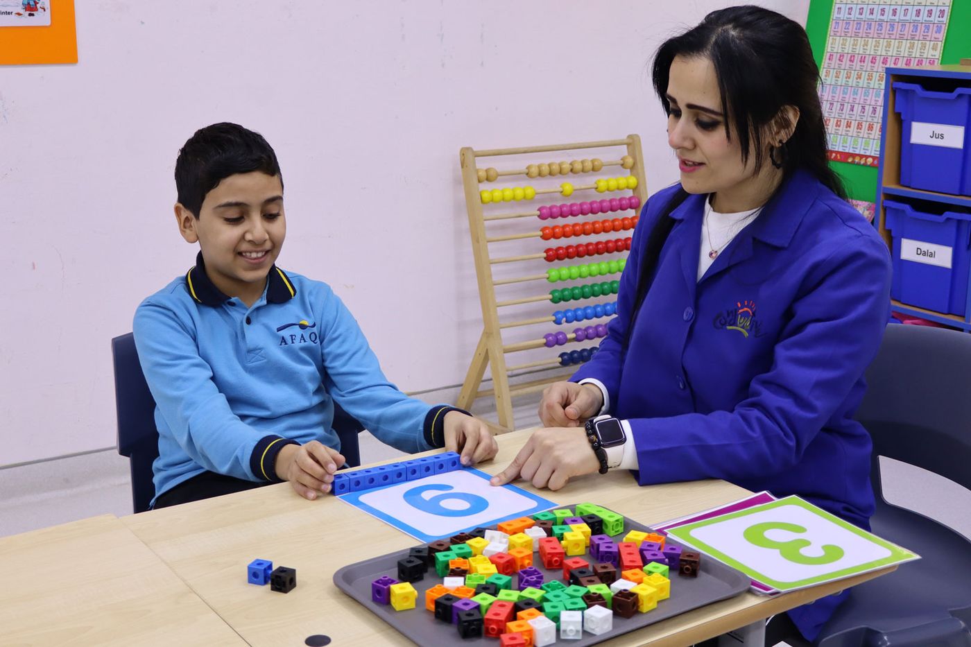 A CESK student working with a teacher on a number and counting activity using coloured cubes