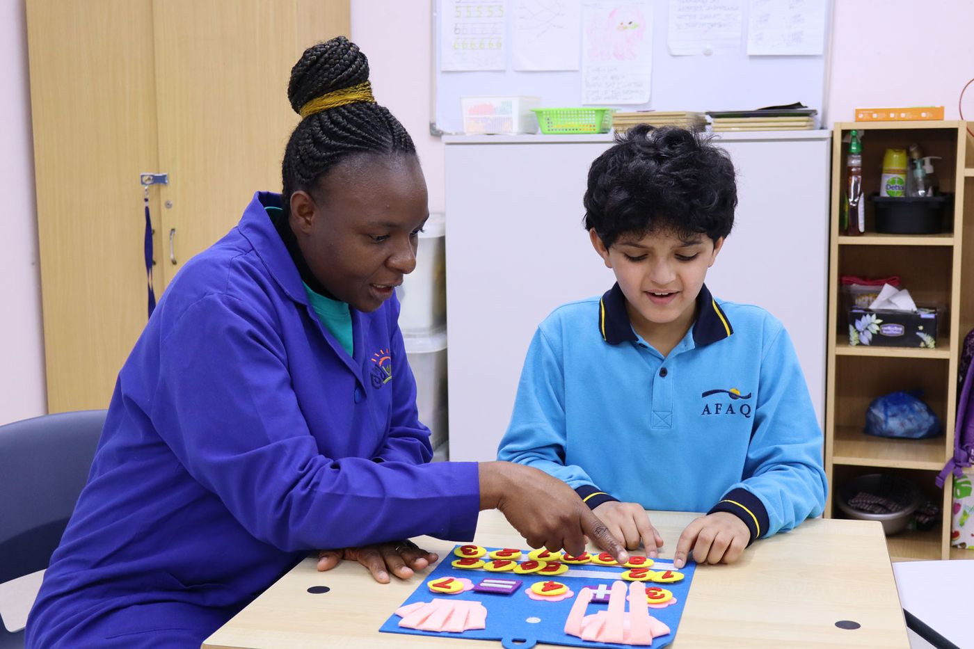A CESK teacher guiding a smiling student through a hands-on learning activity