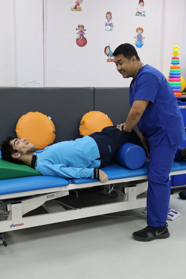 A CESK physical therapist supporting a student during an exercise on a therapy bed