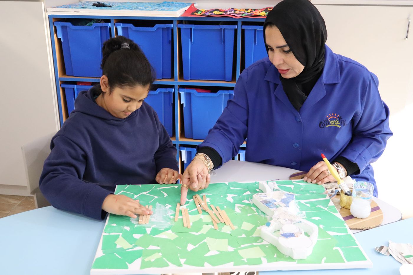 A CESK teacher and student working together on a table-top craft and learning activity